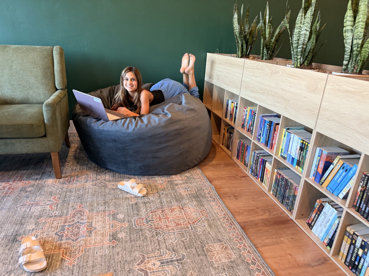 A student working happily on a laptop in a beanbag chair at Redefine Learning Academy